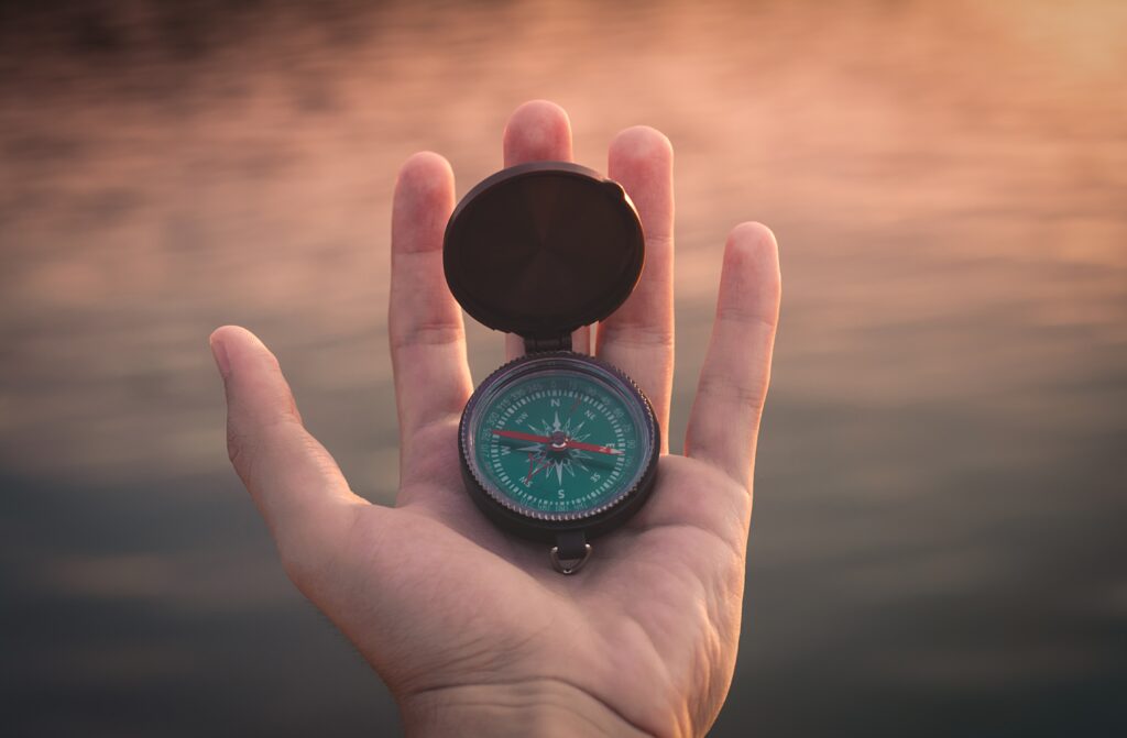 an extended hand holding a compass