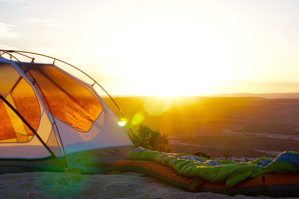 image of sleeping bags and tents against a sunset.